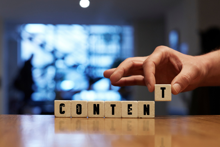 Hand putting letters onto table to spell out the word "Content"