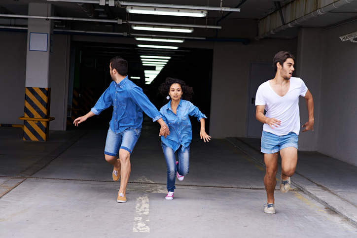 Young people running from parking garage and one young man looking back