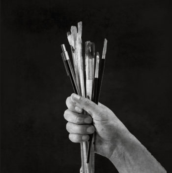 Hand holding paintbrushes